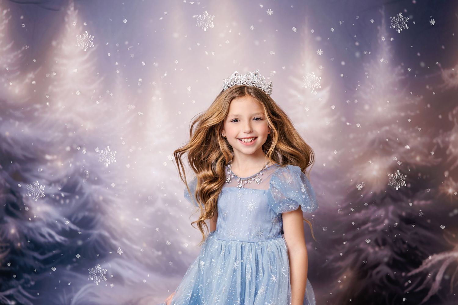 Young girl in blue princess dress and crown poses in winter wonderland snow photography backdrop.