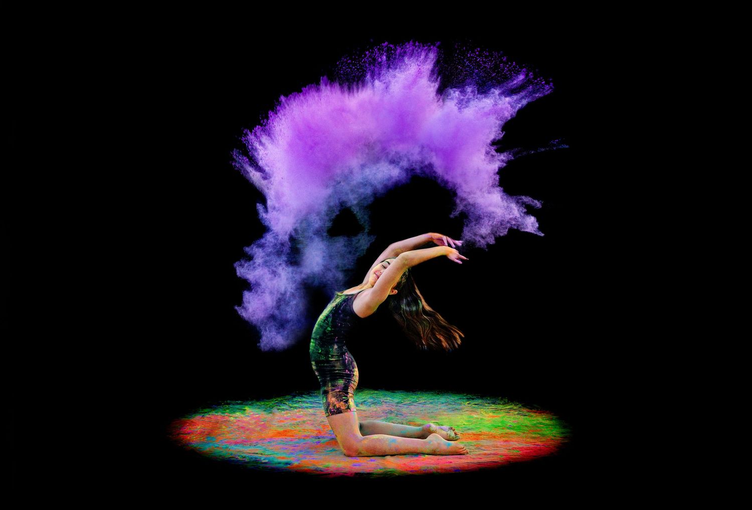 Gymnast performs backbend pose with stunning purple powder cloud swirling overhead on dark background.