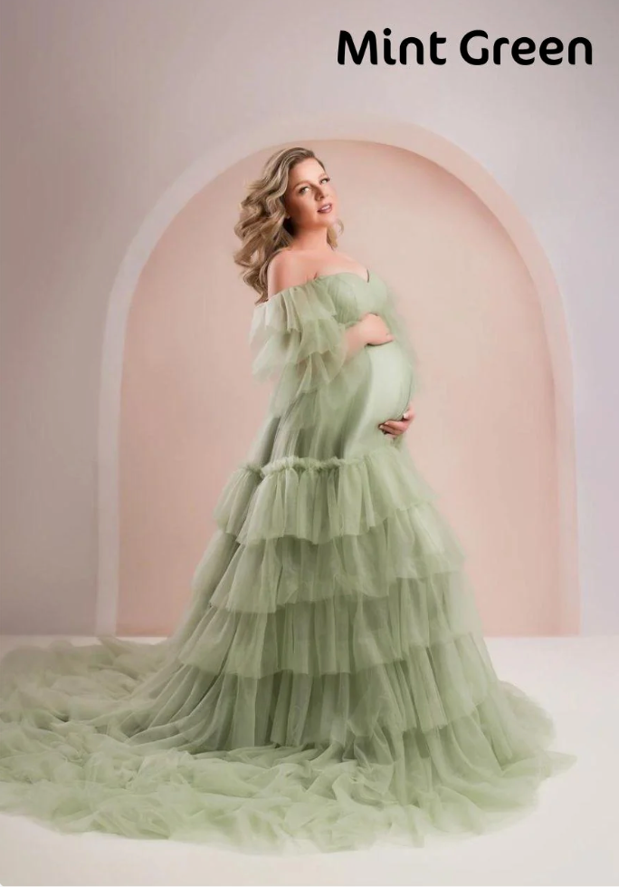 Pregnant woman in mint green tiered ruffle tulle off-shoulder maternity gown with long train.