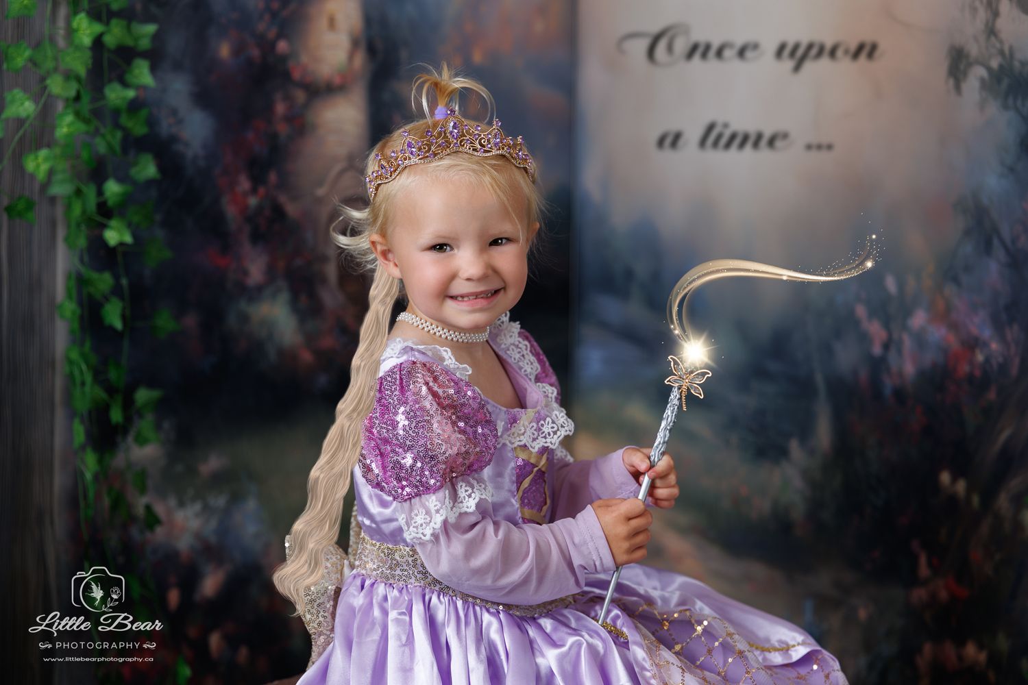 A smiling toddler girl dressed as Rapunzel in a purple princess gown holds a sparkle wand in a fairytale portrait.