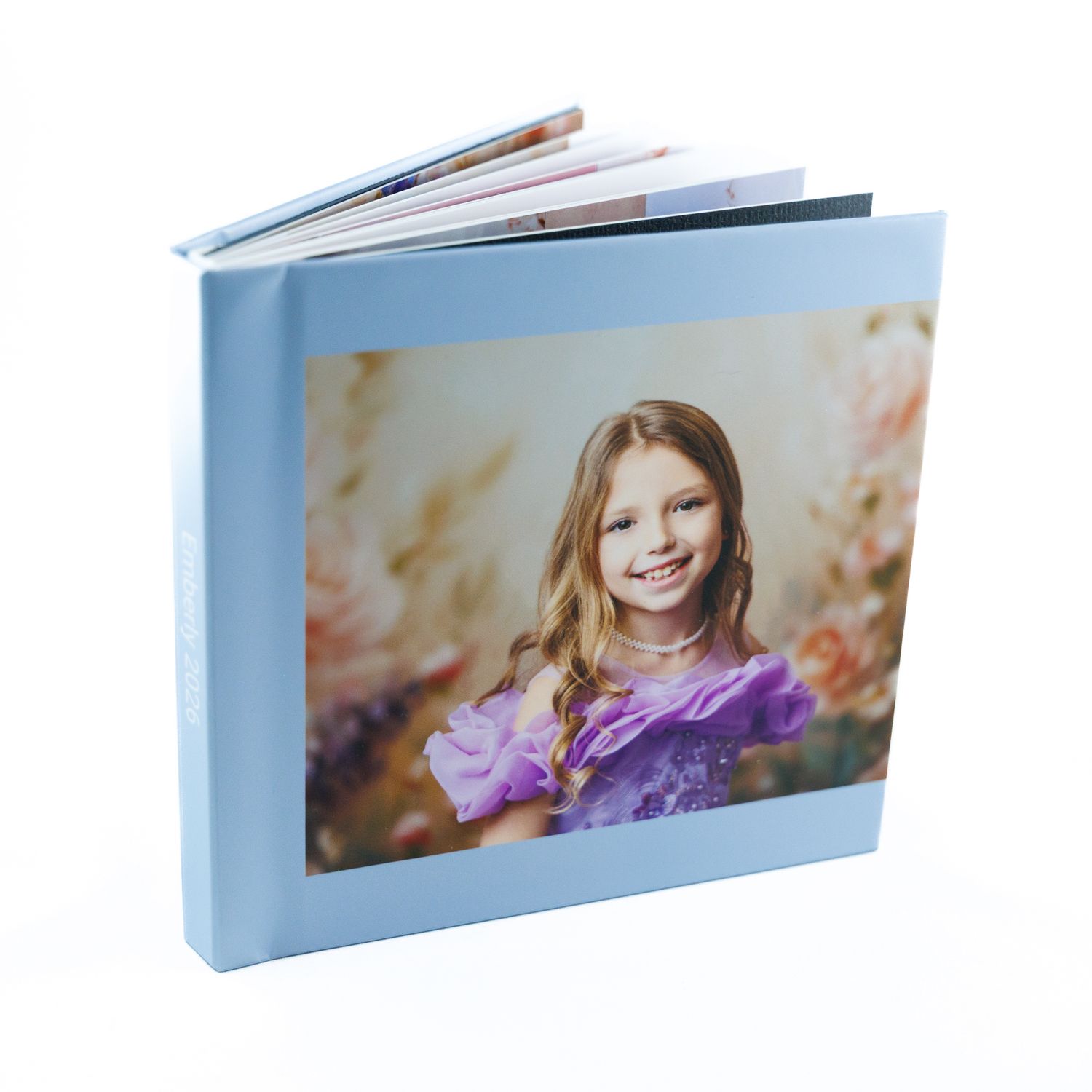 Light blue hardcover children's photo book featuring smiling girl in purple dress on cover.