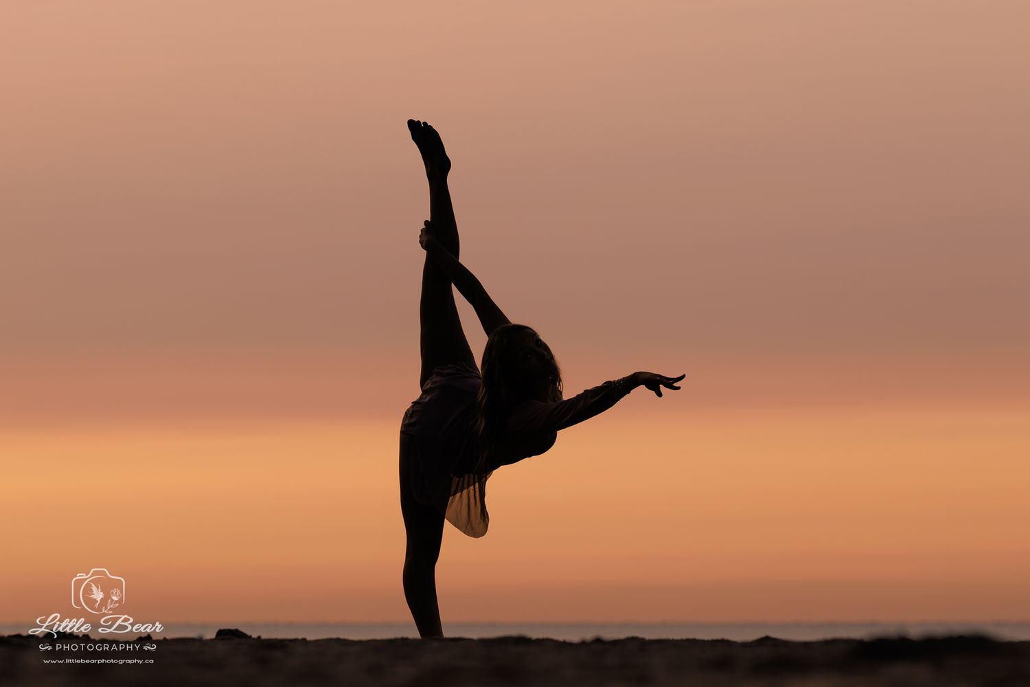 Silhouette of a dancer performing a graceful high kick pose against a warm golden sunset sky.