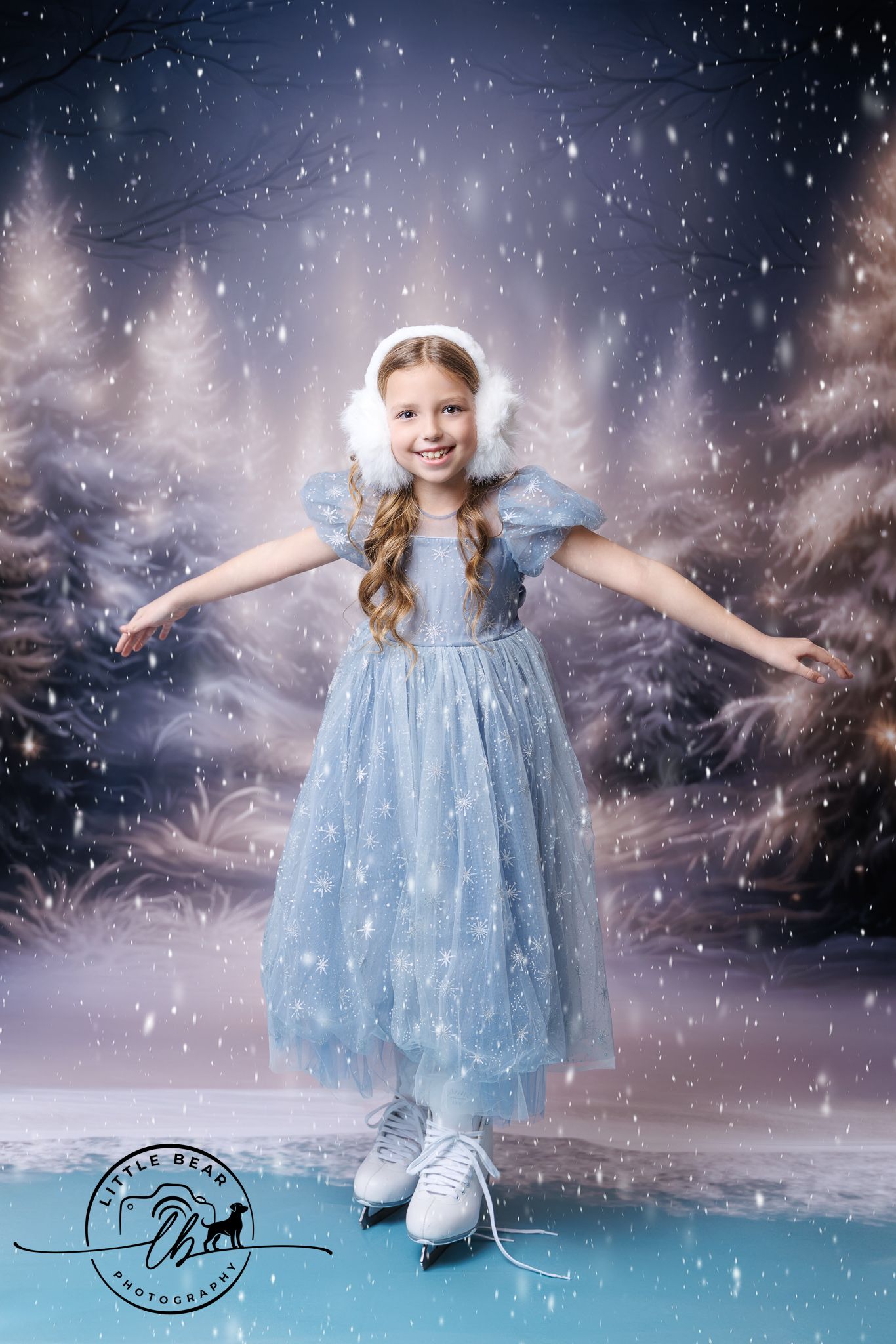 Smiling girl in a blue sparkle dress with white ice skates posing in a snowy winter wonderland backdrop.