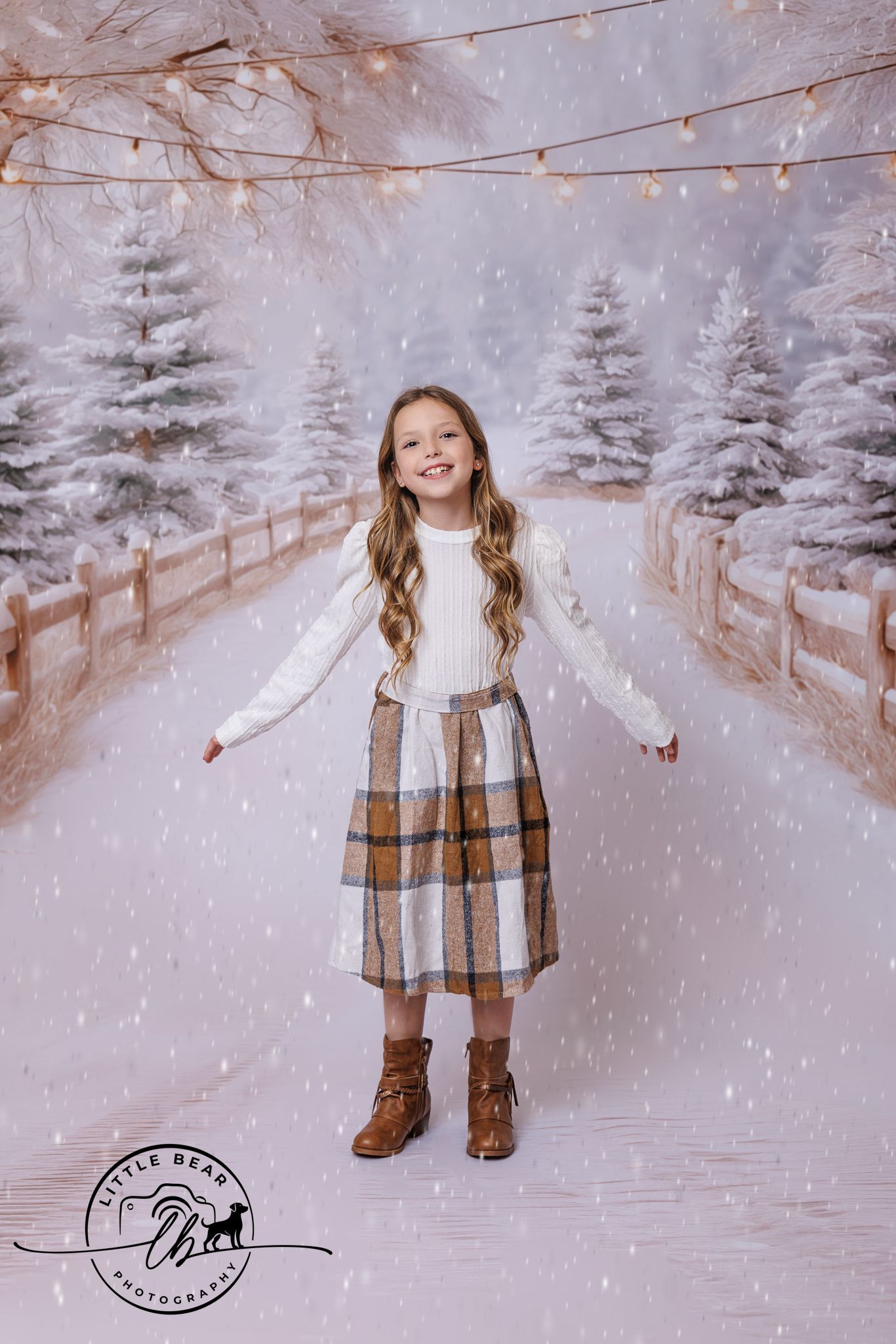 A smiling girl in a plaid skirt and white sweater poses in a snowy winter wonderland backdrop with fairy lights.