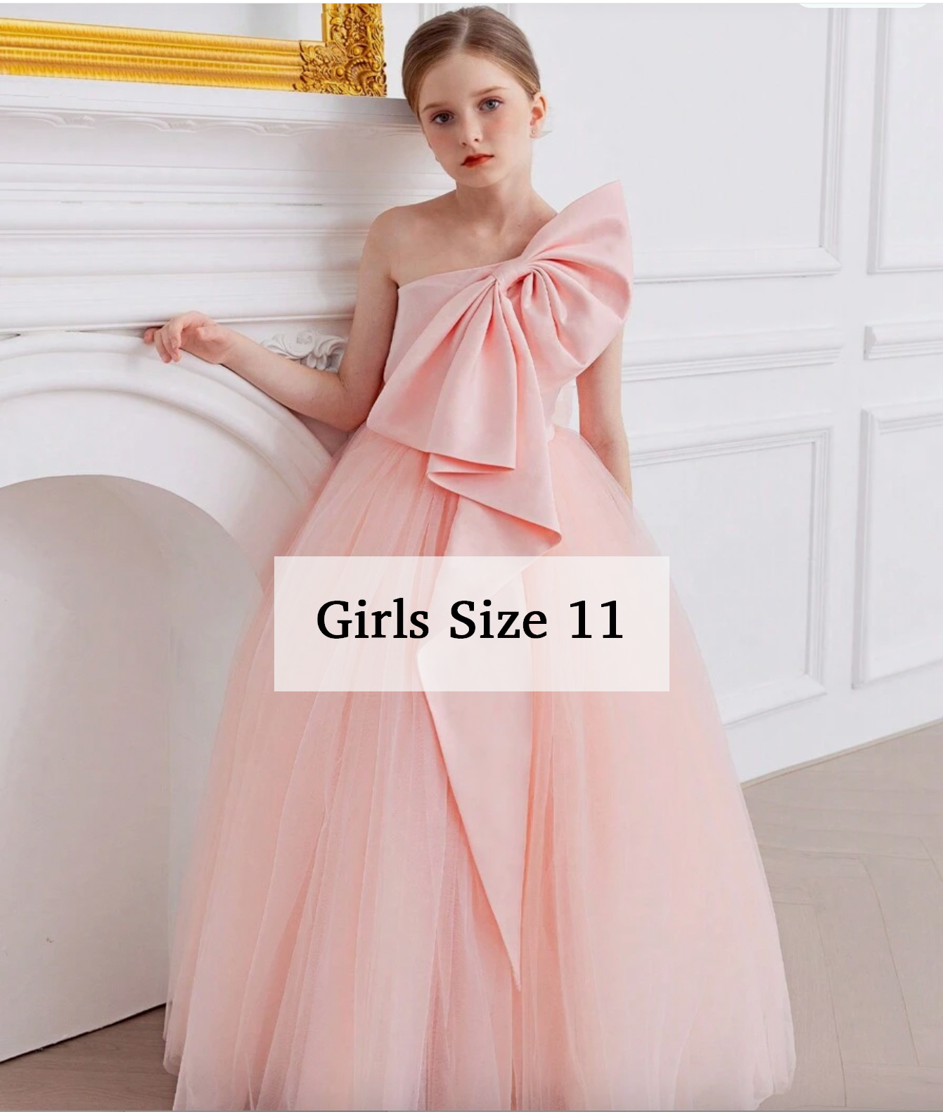 Girl wearing a blush pink one-shoulder tulle ball gown with large bow, floor-length formal dress in size 11.