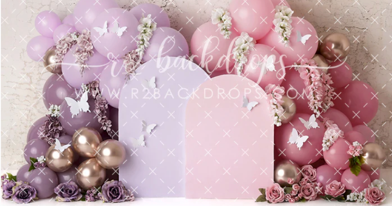 Pink and purple balloon arch backdrop with butterflies and flowers, ideal for children's party photography.