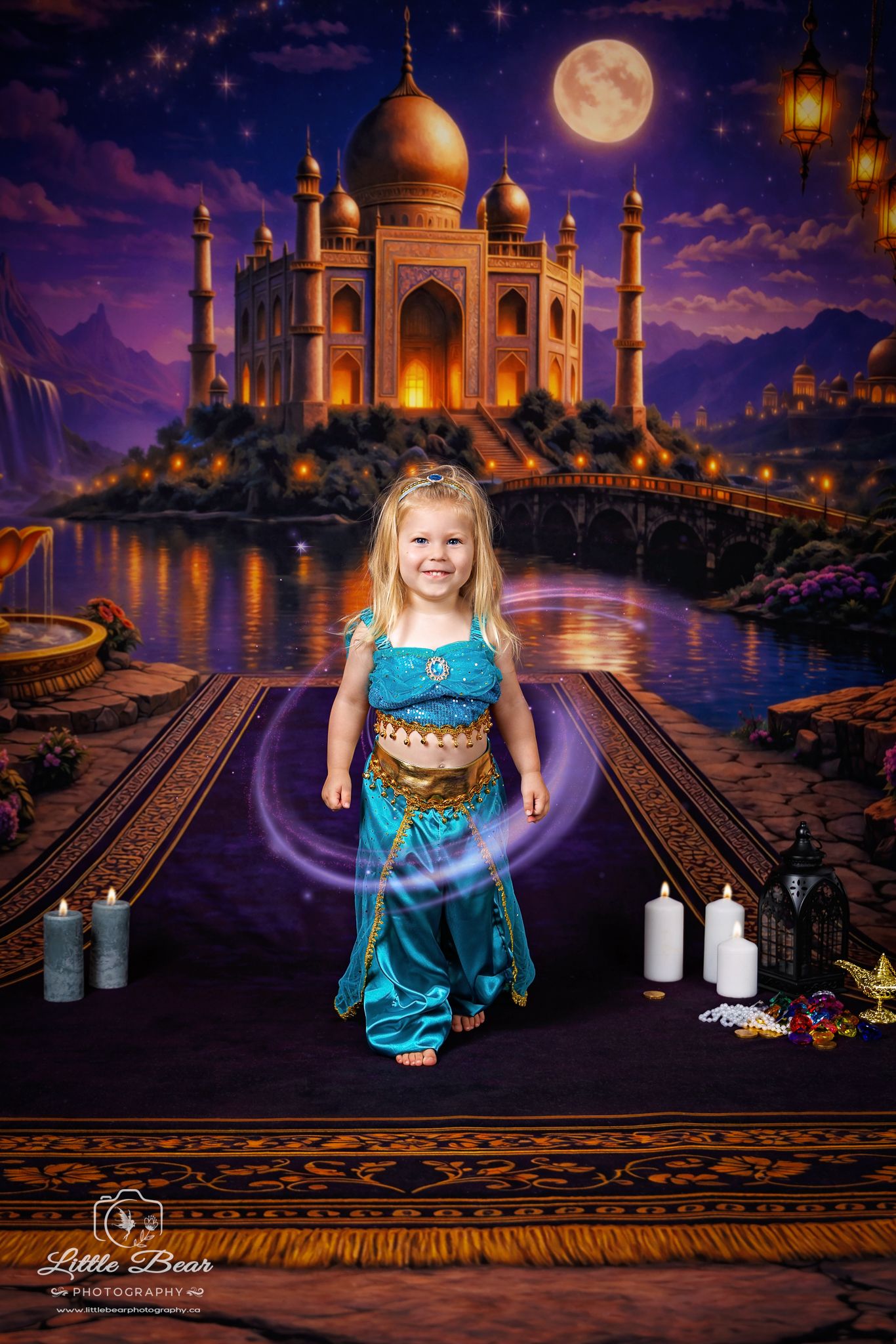 Little girl dressed as Princess Jasmine poses on magic carpet before illuminated palace backdrop at night.