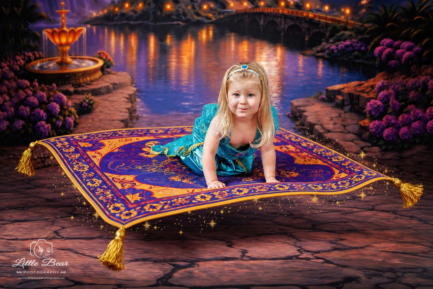 Young girl in teal costume poses on magic carpet in enchanted garden setting inspired by Aladdin.