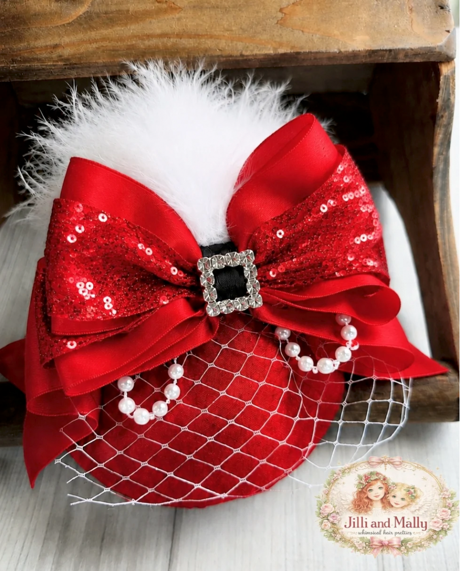 Red sequin bow hair clip with white feathers, pearl beads, rhinestone buckle, and birdcage veil for festive style.