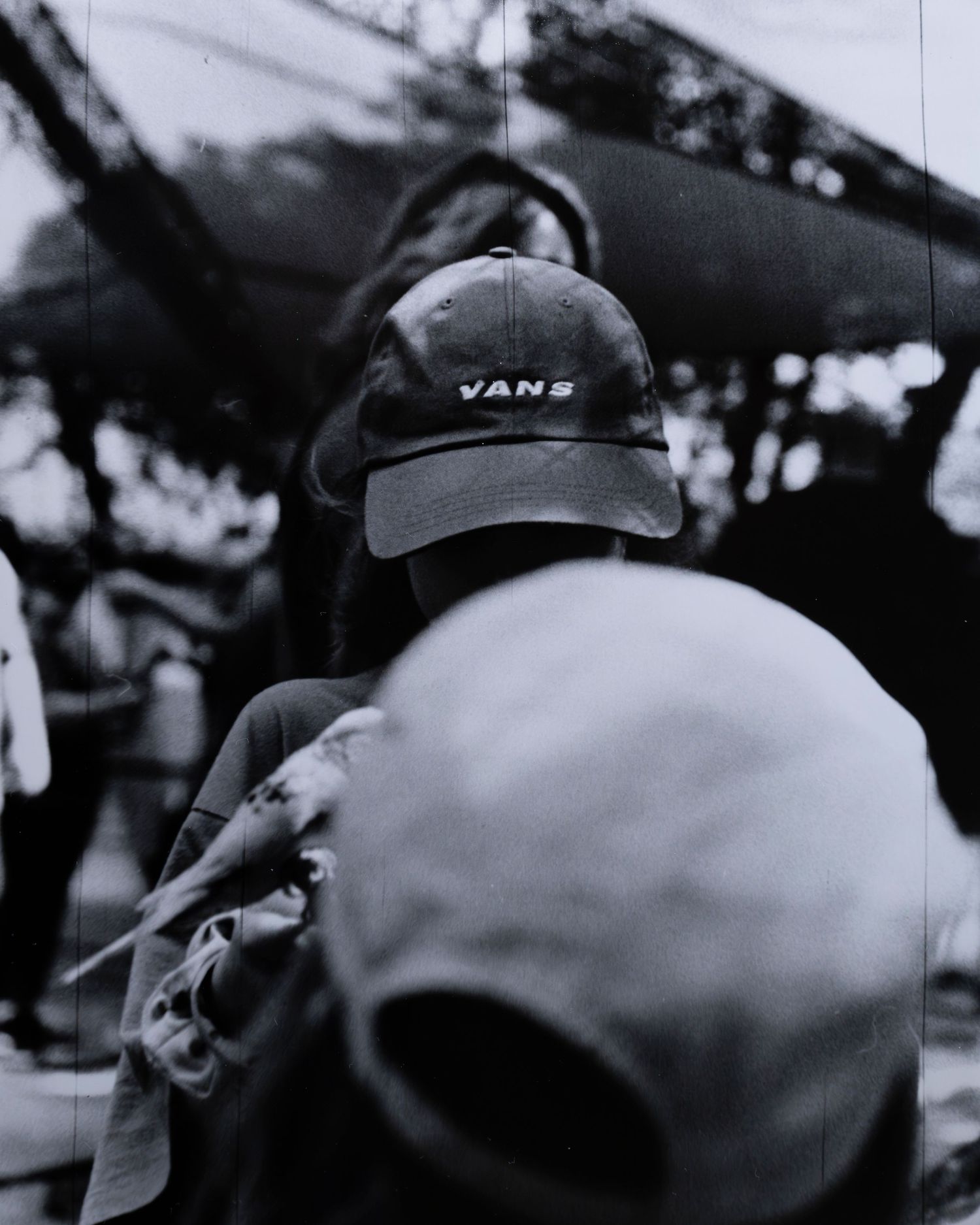 Black and white photo of child wearing a Vans cap holding a bird at the zoo.