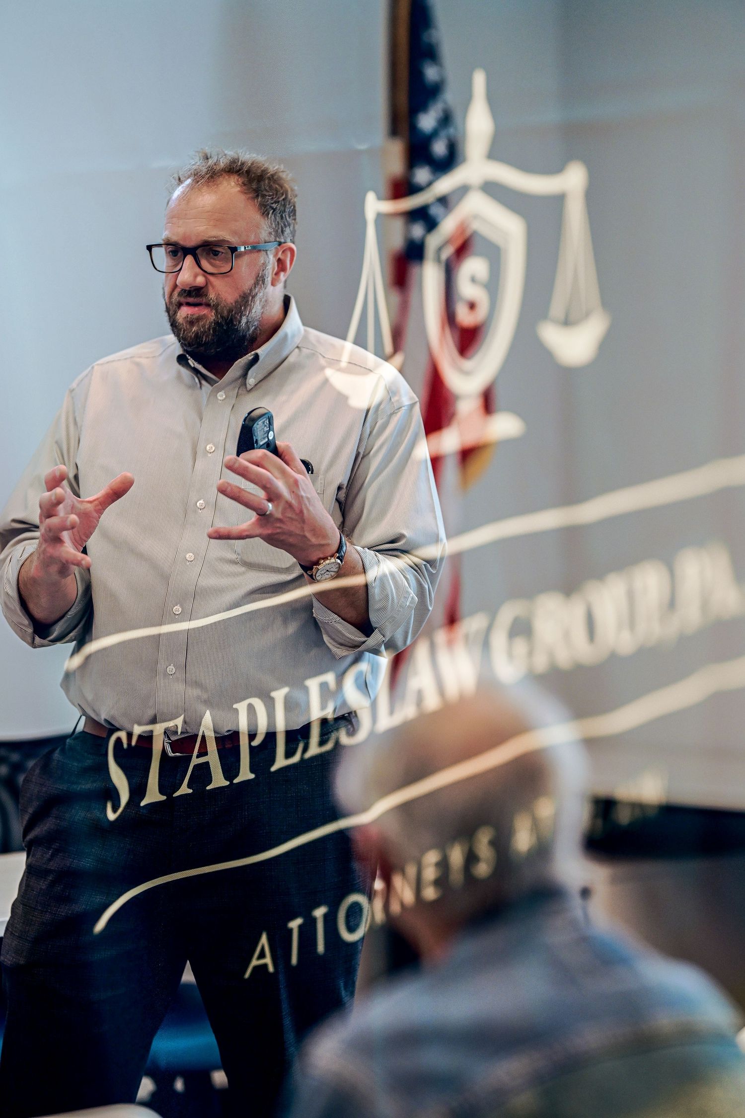 Bearded man in glasses speaking passionately at Staples Law Group PA office.