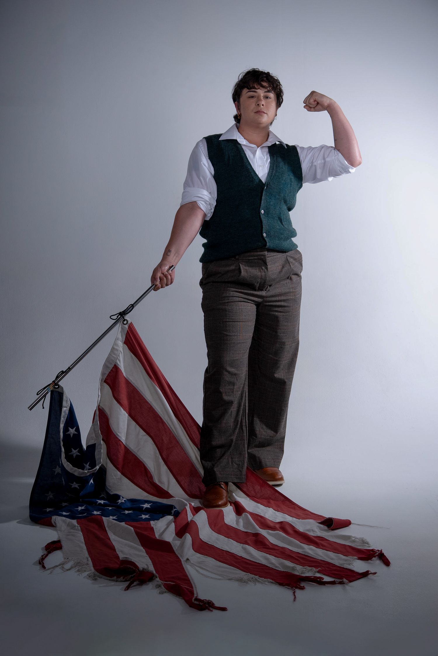 Photograph of young man flexing and standing on the American flag. Photographed at YUQ Studios DTLA, an LA photo production company