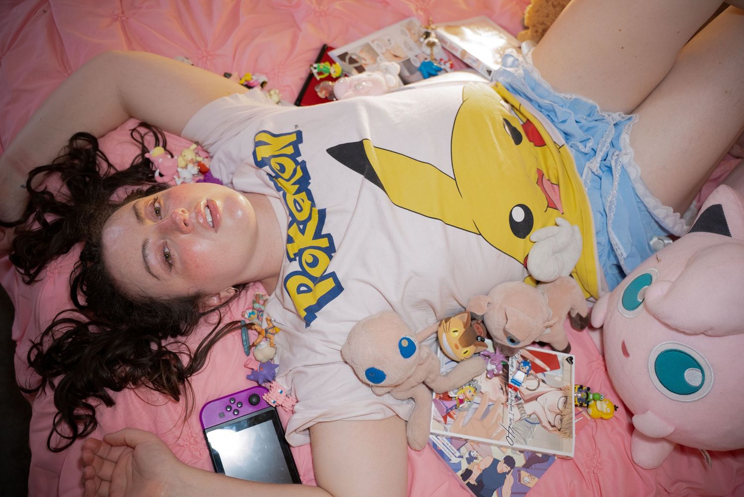 Photograph of a woman laying in bed surrounded by trinkets. Photo was shot by YUQ Studios photographer Calla Faeria