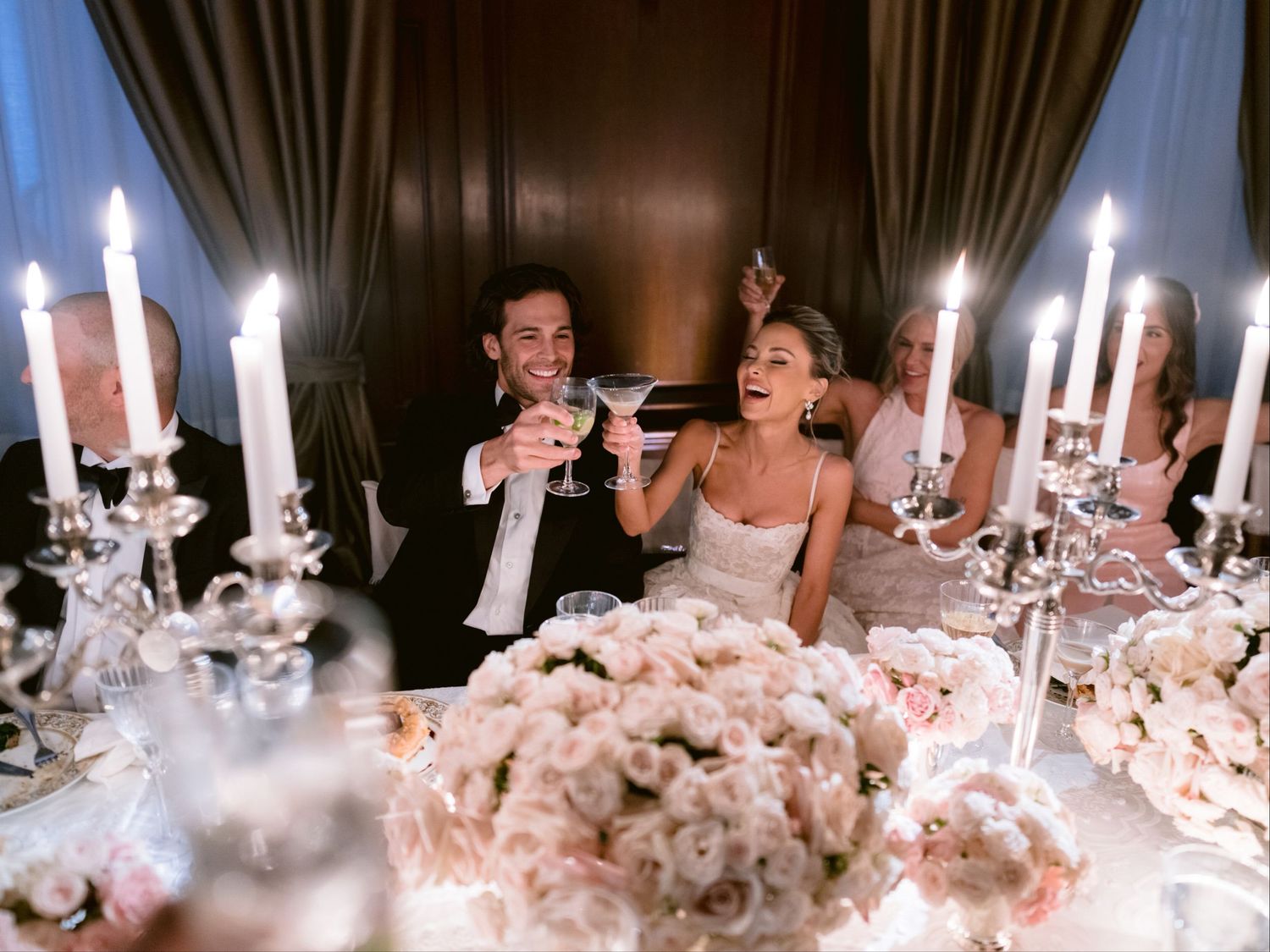 A romantic wedding reception table setting with glowing candles and white floral centerpieces creates an elegant atmosphere.