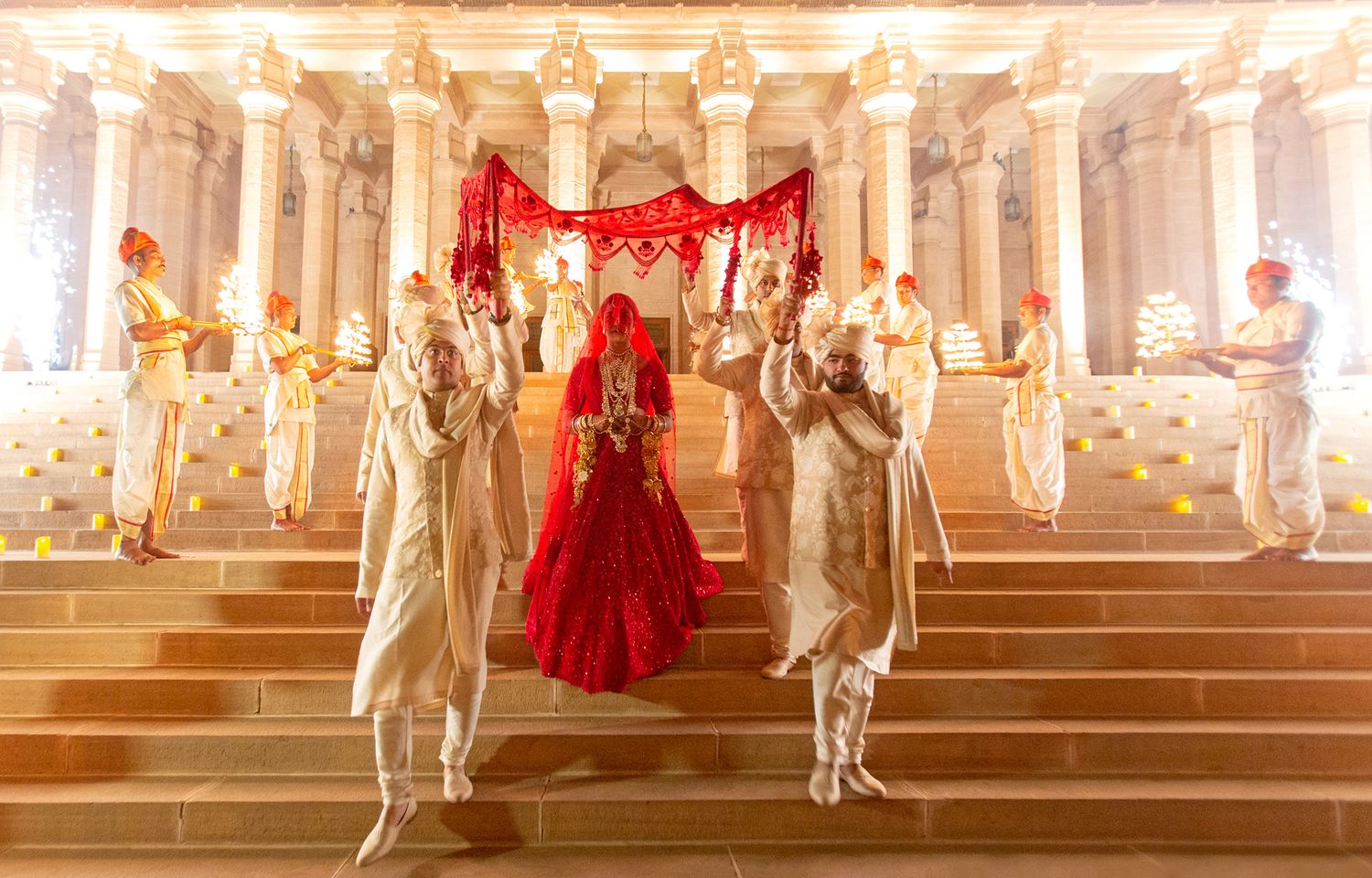 A series of illuminated marble statues and red curtains create a dramatic display in an ornate architectural setting.