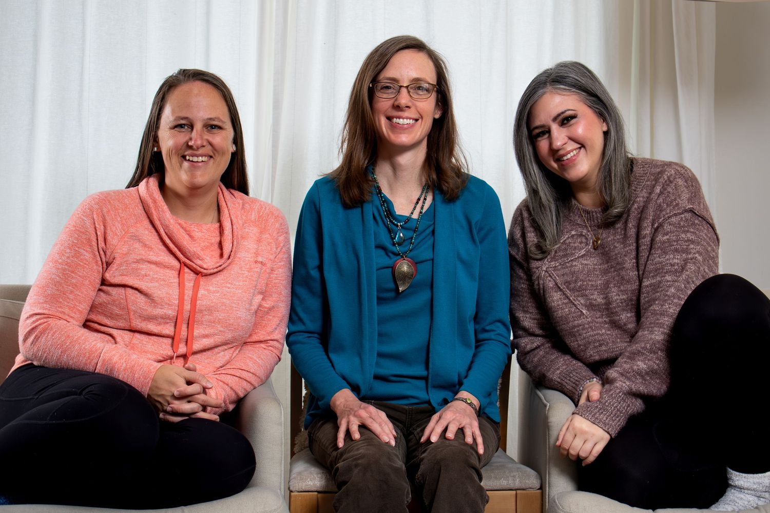 Three colleagues seated together for a business team portrait.