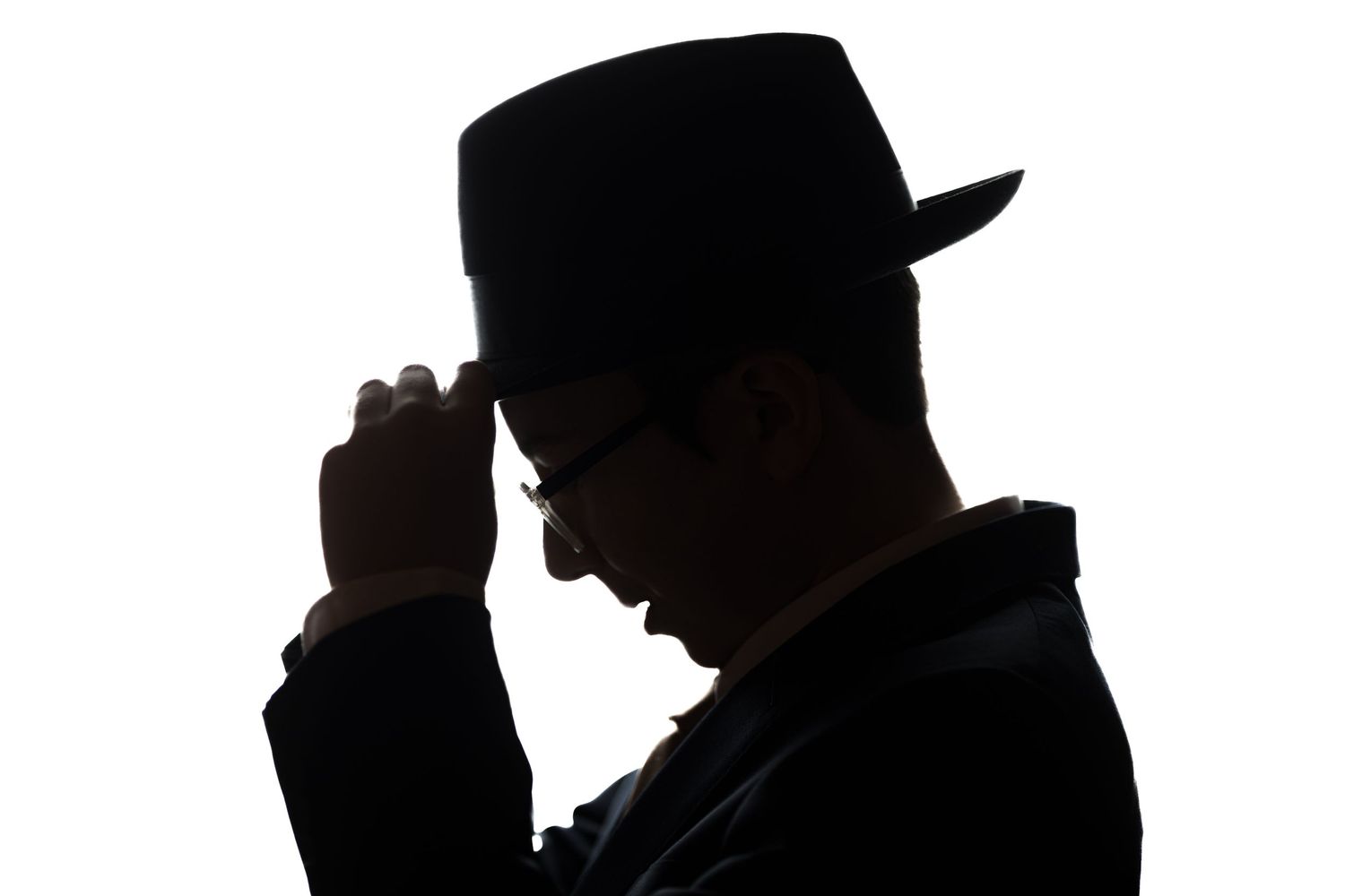 Silhouette of a man in a black hat and suit against a white background.