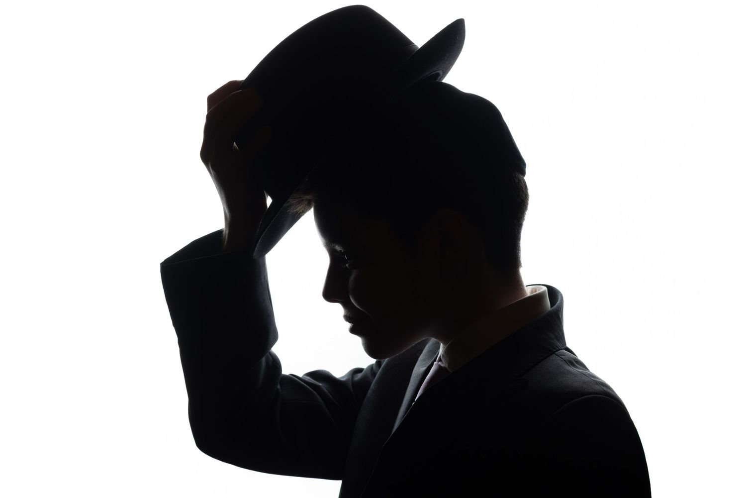 Silhouette of a man tipping his fedora hat against a white background in a classic noir style.