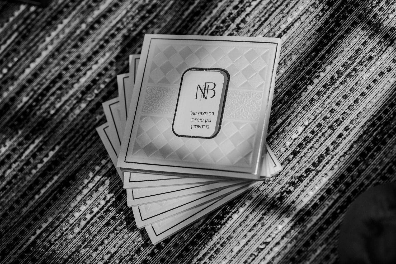 Black and white photo of stacked NB monogram cards on a textured surface.