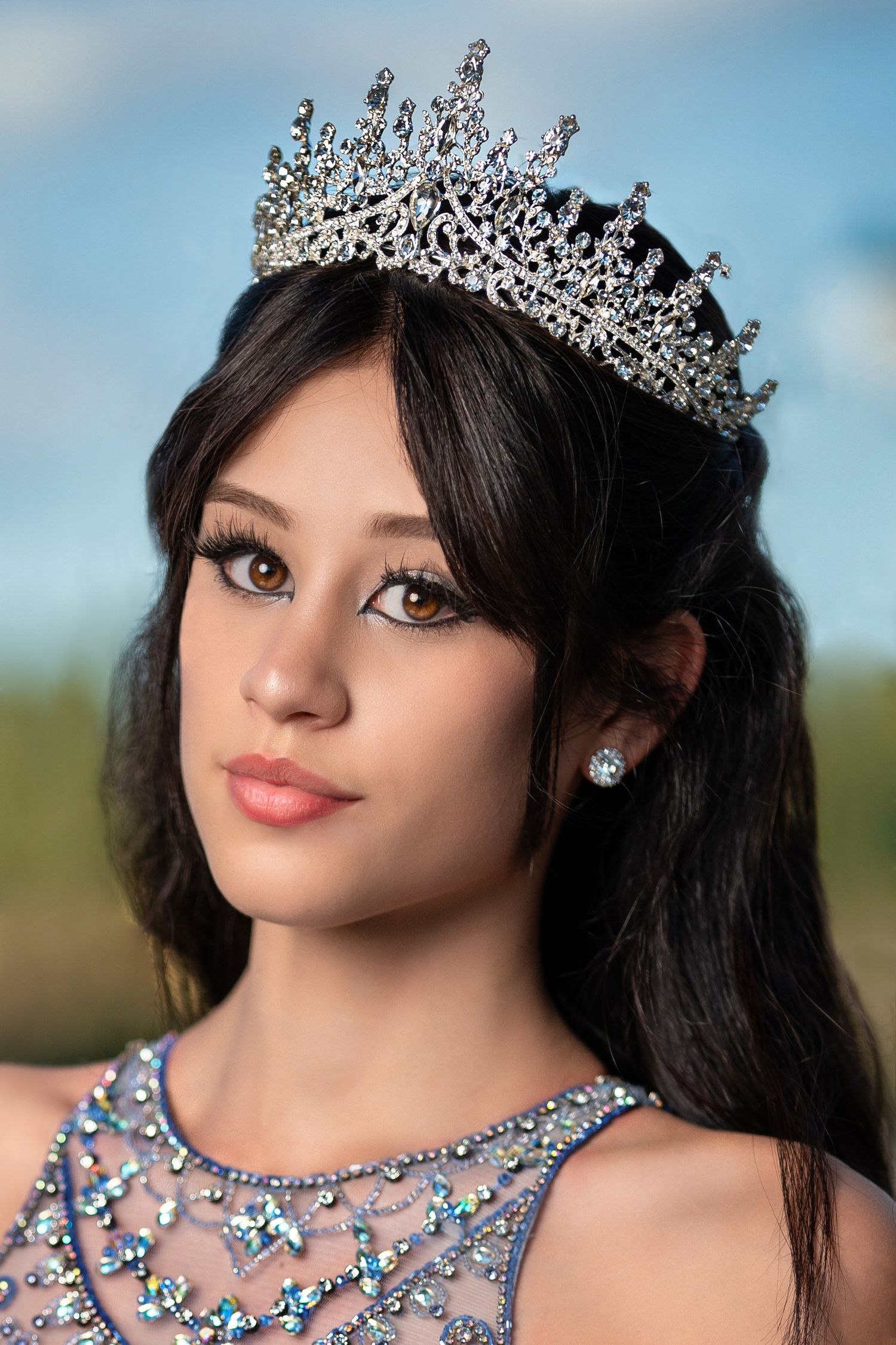 Close-up portrait of a woman wearing ornate crystal crown and embellished dress.