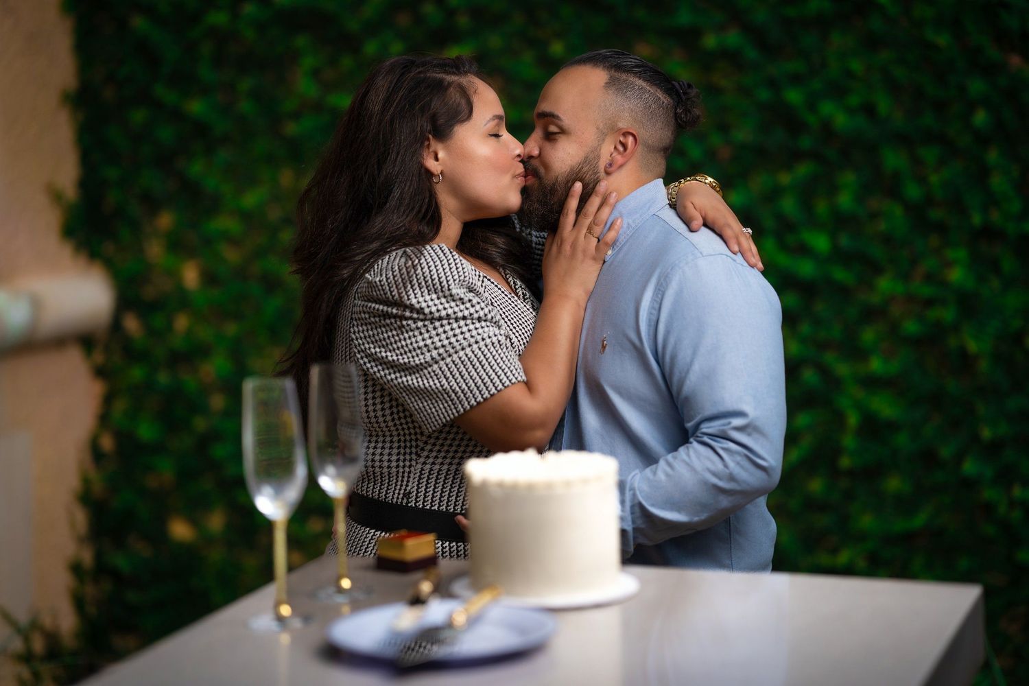 A romantic couple shares an intimate moment at a table with champagne and cake.