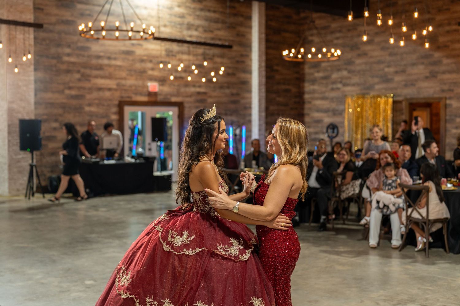 Modern event space with brick walls, chandeliers, and string lights creating a warm atmosphere.