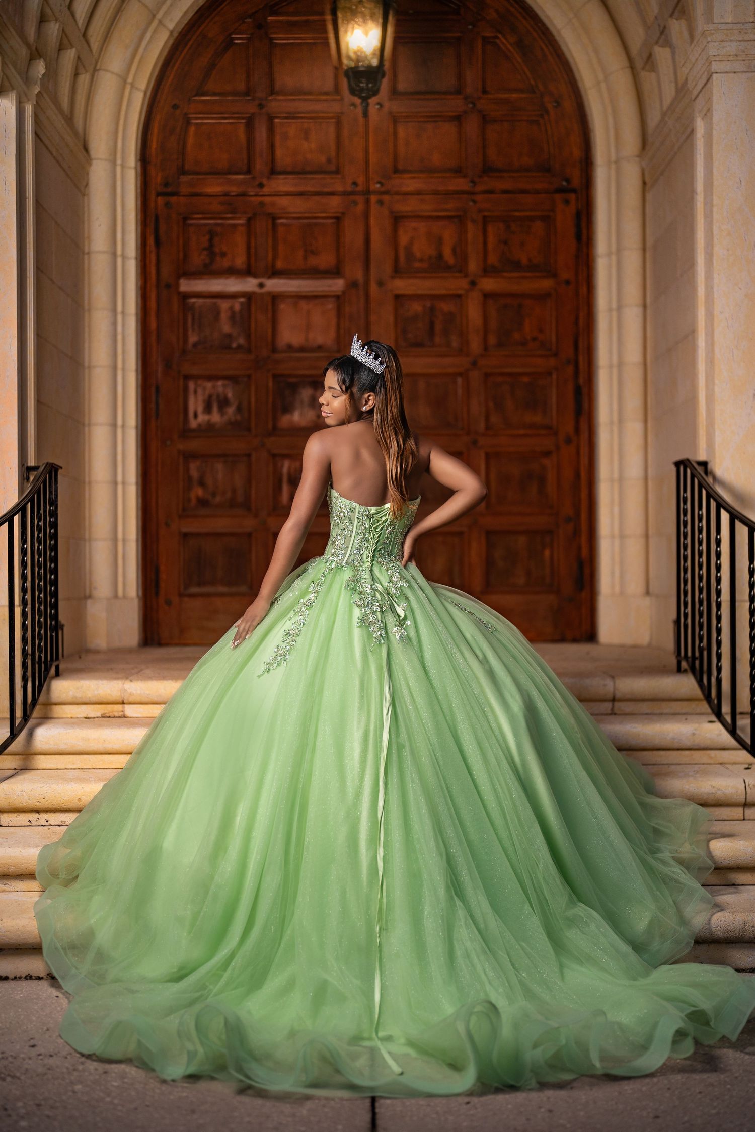 Mint green ball gown with intricate beading photographed against ornate wooden doors and stone archway.