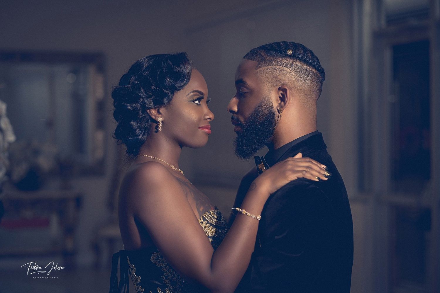 Elegant couple in formal attire sharing an intimate romantic moment, man in velvet suit and woman in embellished gown.