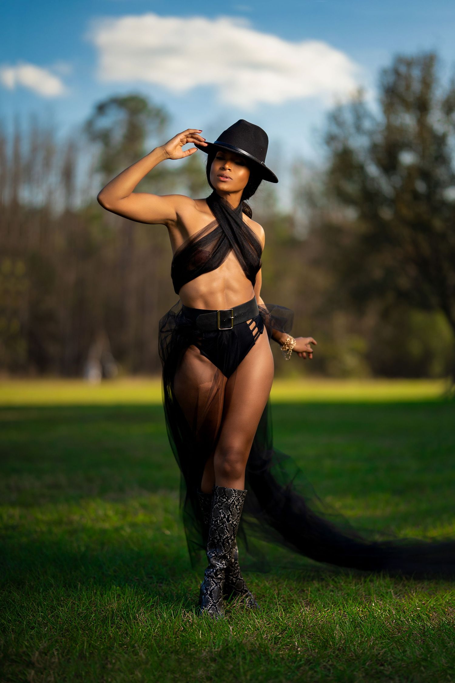 Artistic outdoor portrait session in a grassy field with flowing black fabric.