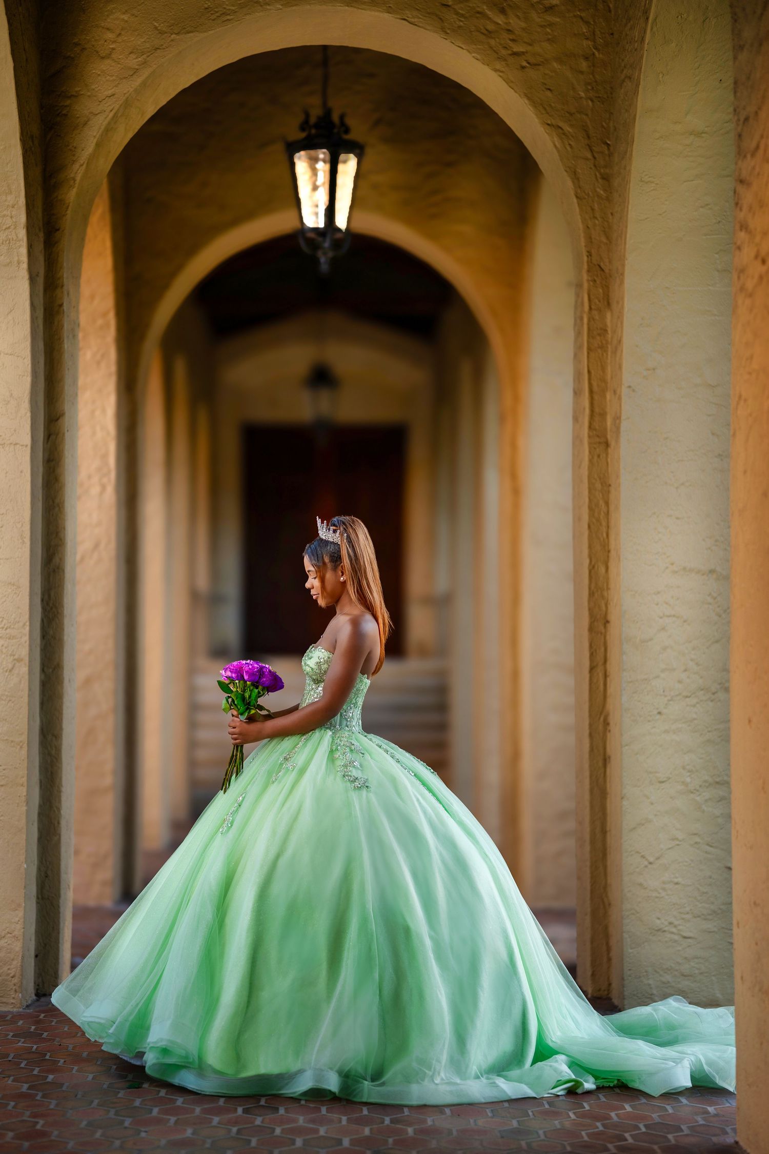 Ethereal mint green ball gown photographed in arched stone corridor with dramatic lighting.
