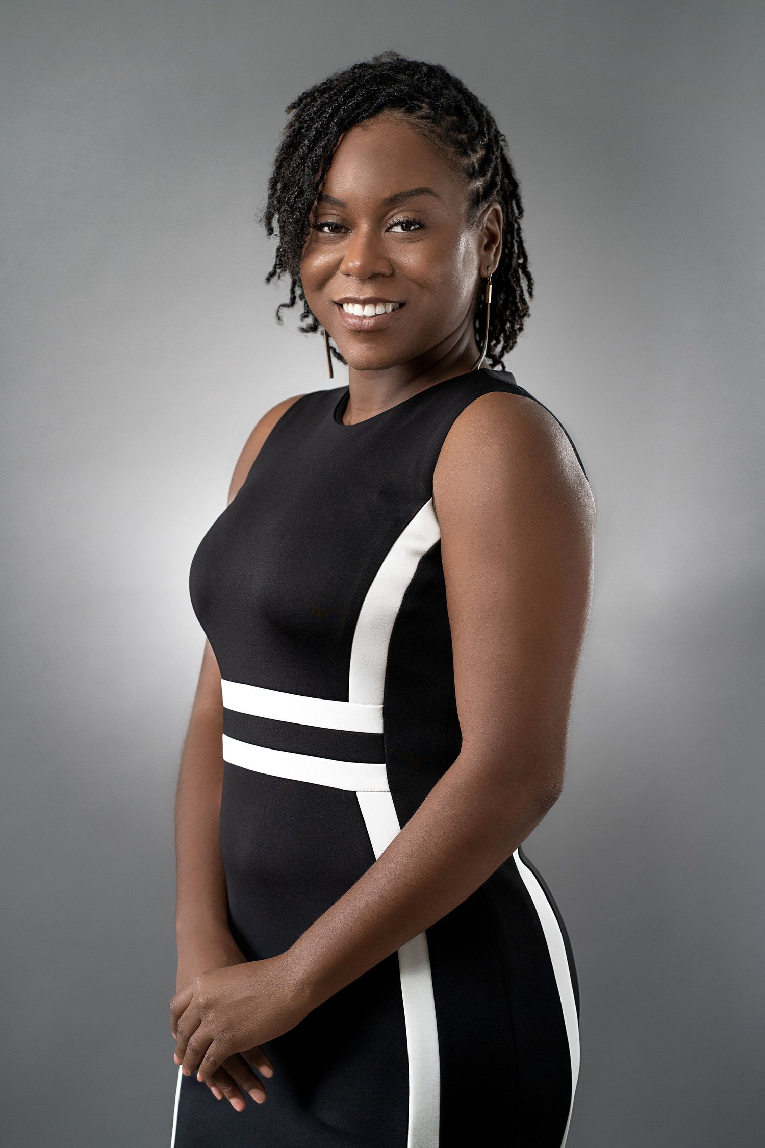 Professional headshot of a woman in a black and white dress with braided hair.