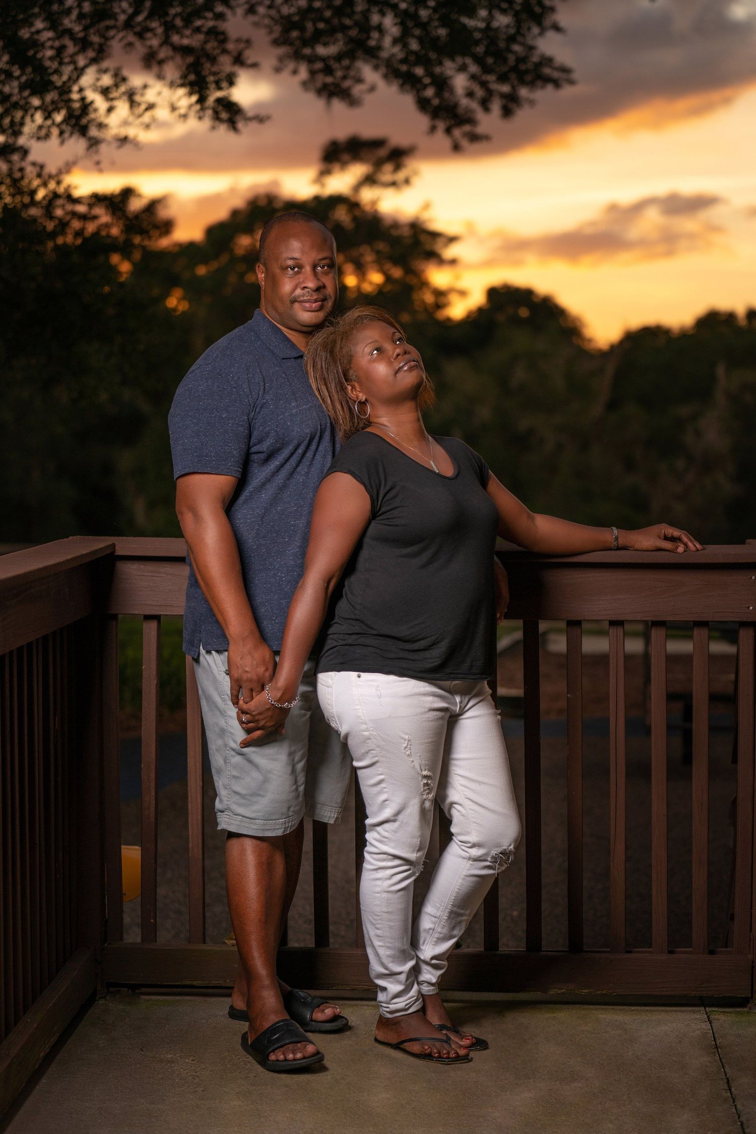 A couple shares an intimate moment on a deck during a vibrant sunset.