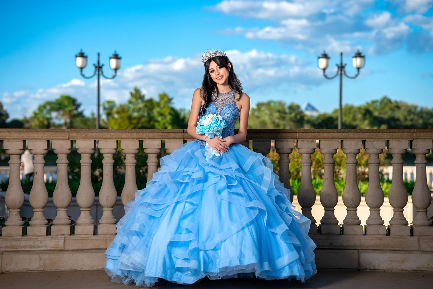 Quinceañera photos featuring a blue ball gown on an elegant stone balcony.