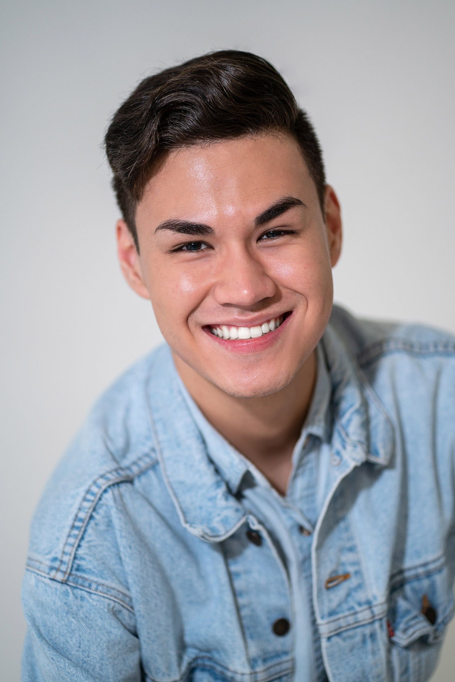 Studio portraits in light denim jacket against white background.