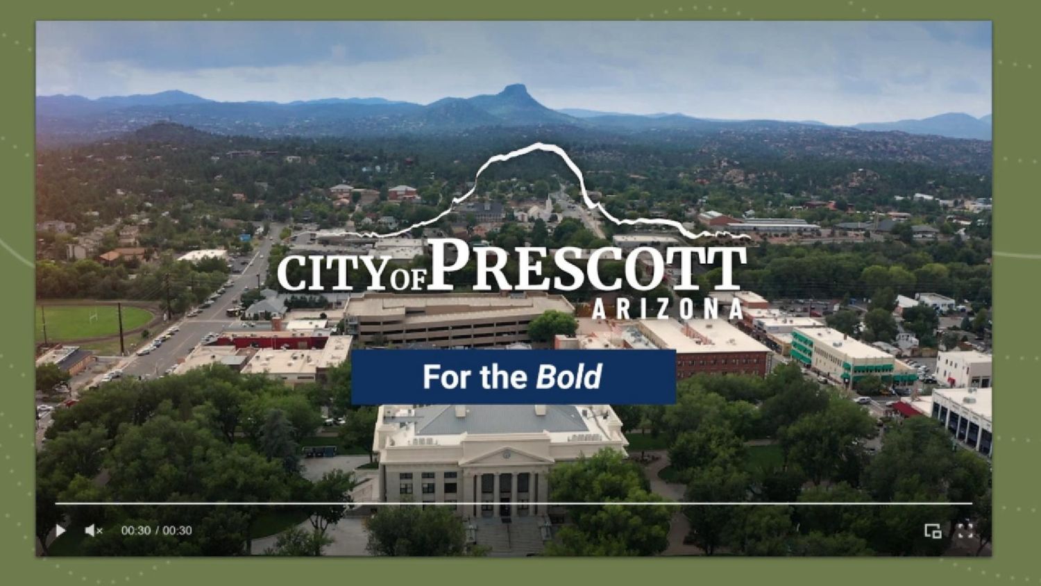 Aerial view of Prescott Arizona with city logo overlay and mountains in background against blue sky.