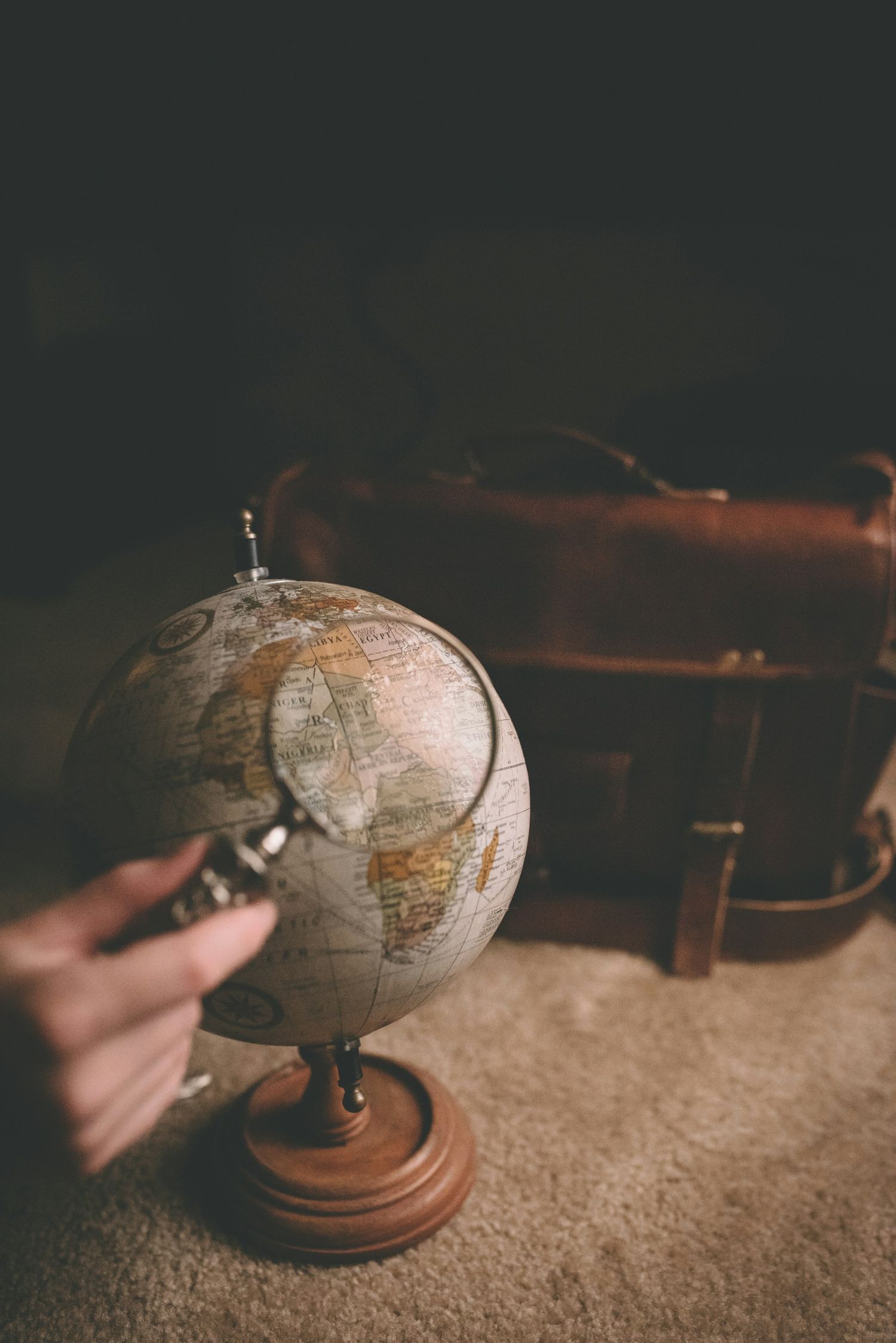 A vintage desktop globe with wooden base shown in a sequence of four moody atmospheric photos.