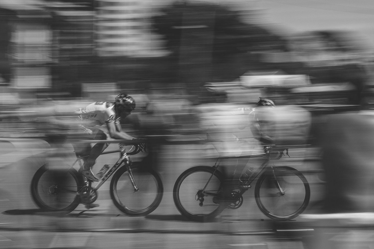 Motion blur of cyclists racing past in black and white photography.
