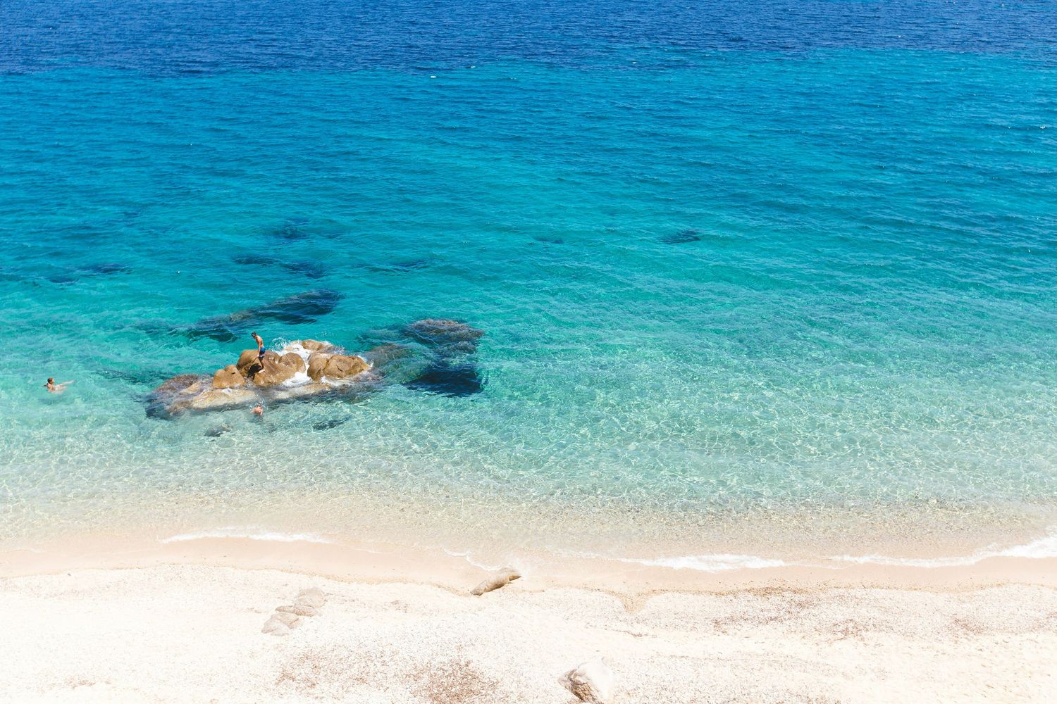 A sequence of aerial photos showing a person snorkeling in crystal clear turquoise waters near a white sandy beach.
