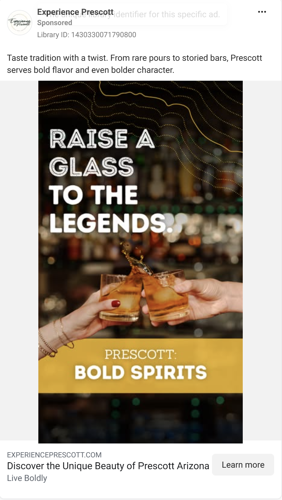 Two hands clink whiskey glasses together in a dimly lit bar setting with warm lighting and bokeh effects in background.