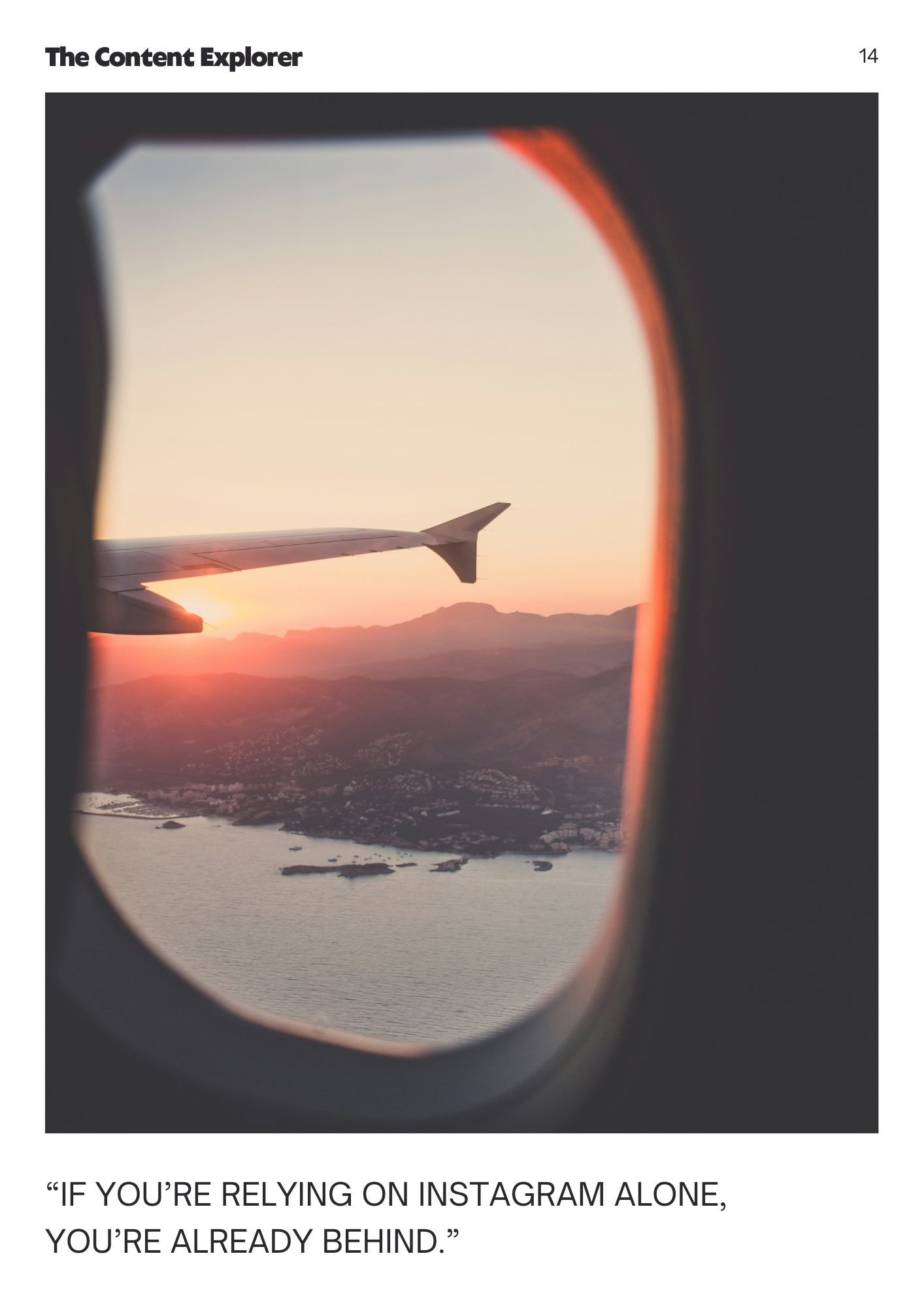 View from airplane window showing wing silhouette against orange sunset sky over coastal landscape and water below.