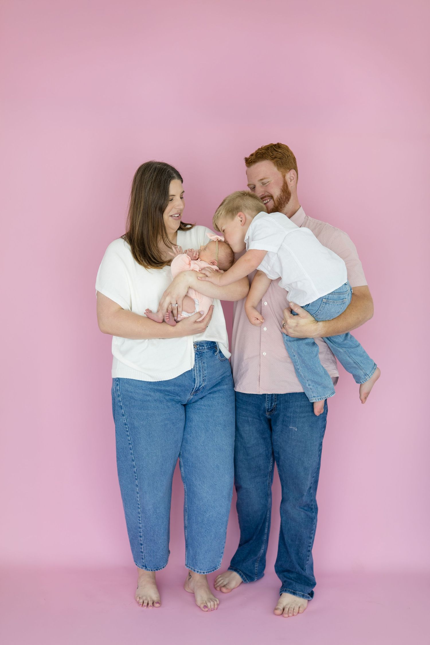 Older brother kisses younger sister during lifestyle newborn session in the summer at McKinney studio with Reagan Marie Photoraphy
