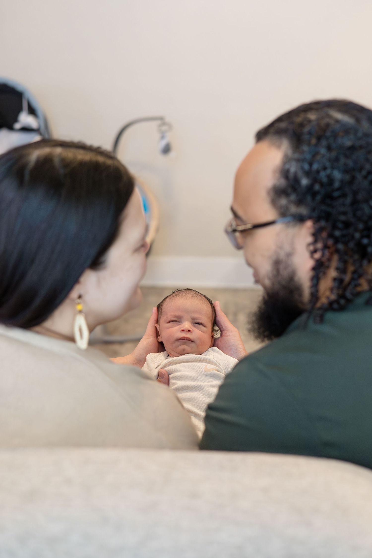 mom and dad look at one another during lifestyle newborn session in home in McKinney, TX with photographer Reagan Marie Photography