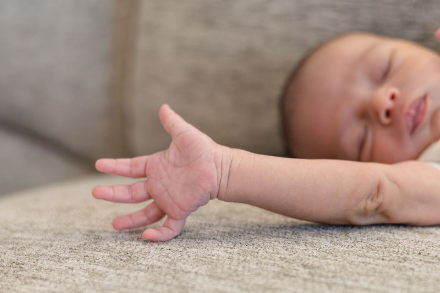 Newborn baby boy lays on couch during lifestyle newborn session with Reagan Marie Photography in McKinney, TX