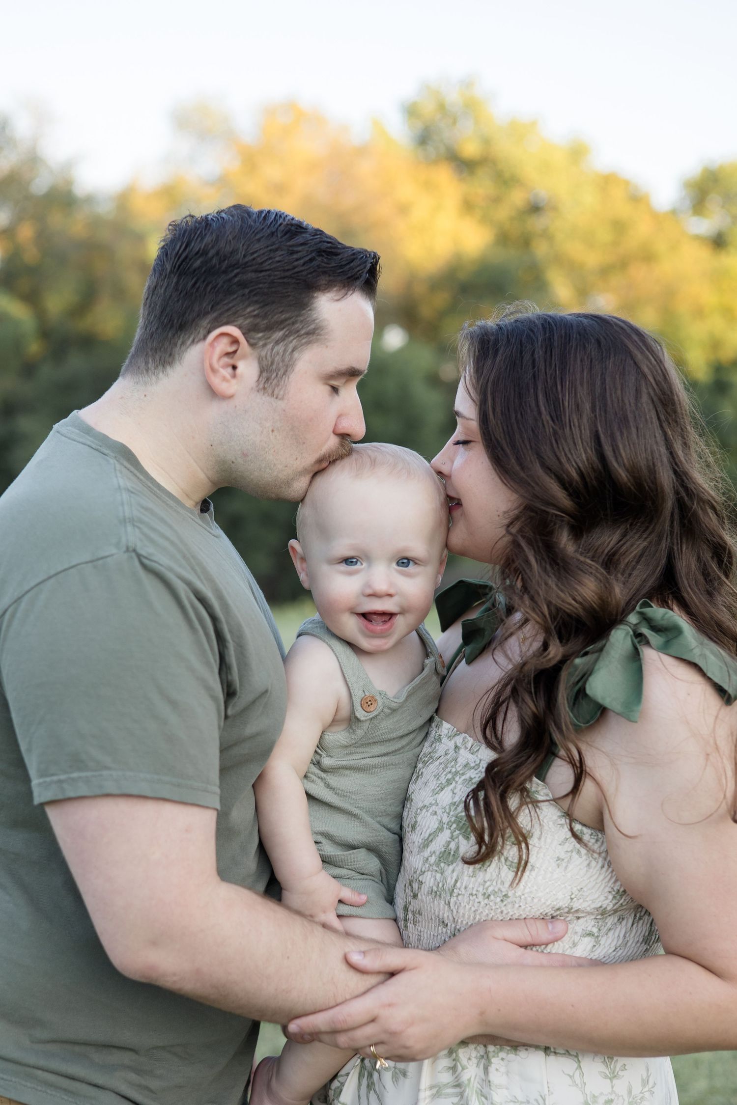 Parents kiss son during family portrait session in the fall at Erwin Park in McKinney, Texas with McKinney Family Photographer