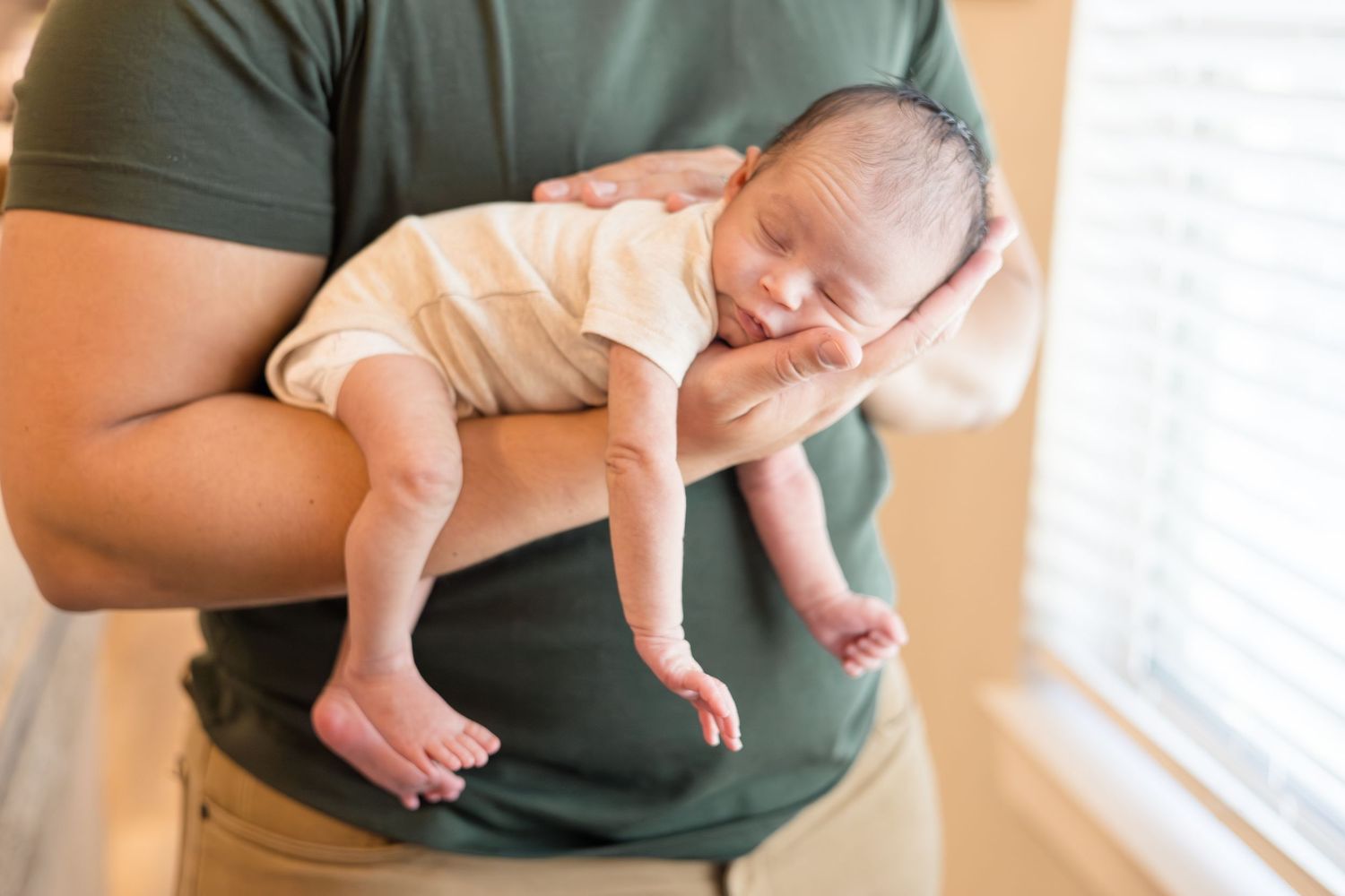 dad holds newborn son during in home lifestyle newborn session with McKinney Photographer Reagan Marie Photography based in McKinney, TX