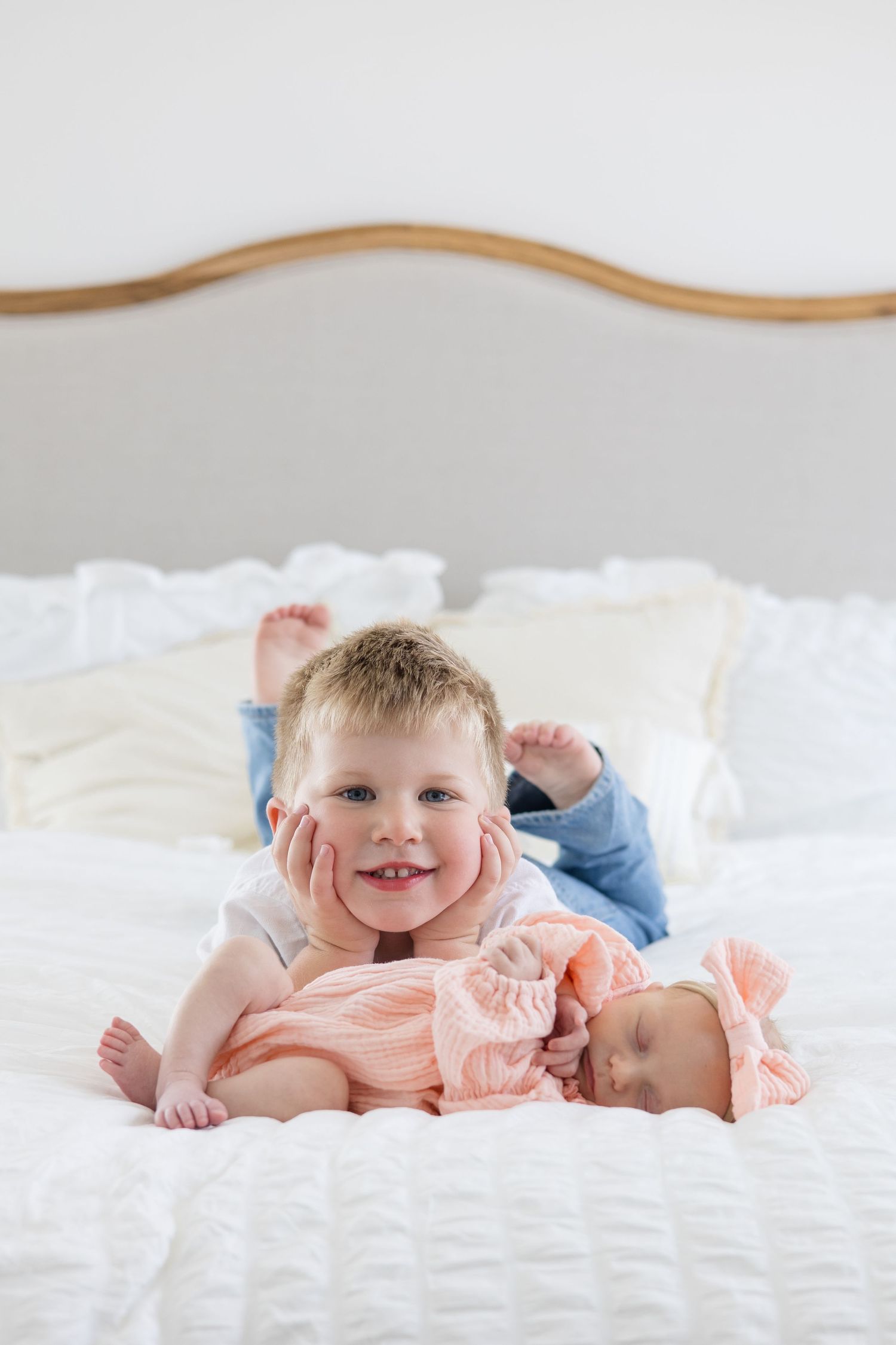 Young boy and newborn girl lay on bed during lifestyle newborn session with family photographer Reagan Marie Photography in McKinney, TX