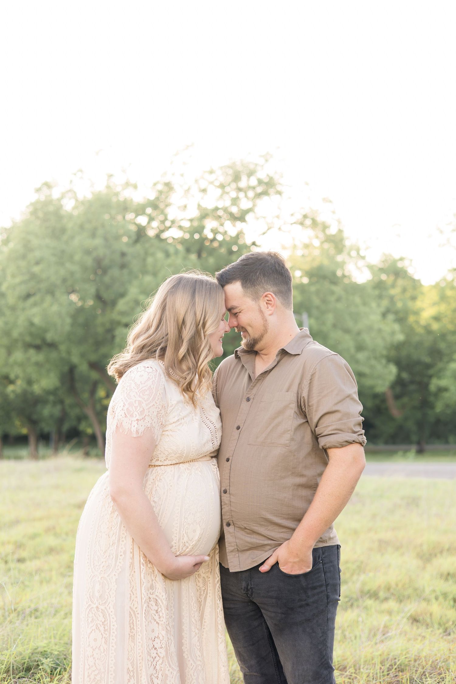 Mom and dad touch noses while mom holds pregnant belly during maternity session at Erwin Park with mckinney maternity photographer