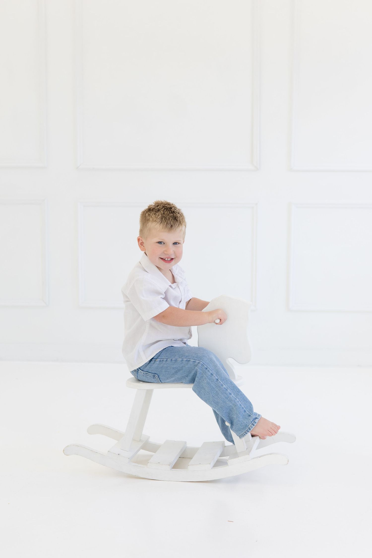 Brother sits on rocking horse during lifestyle newborn session at Lemon Drop Studio in McKinney TX with McKinney family photographer