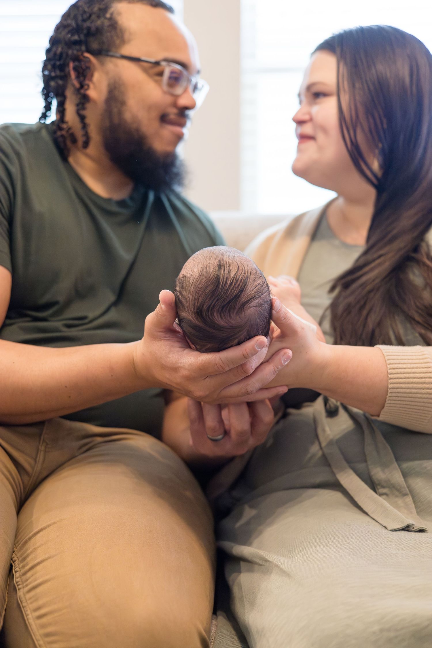 mom and dad look at one another during lifestyle newborn session in home in McKinney, TX with photographer Reagan Marie Photography