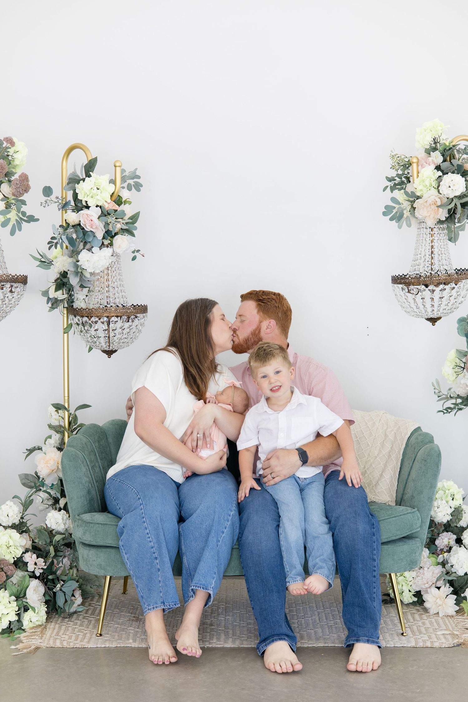 mom and dad sit together with children on couch during summer newborn session with McKinney based photographer Reagan Marie Photography